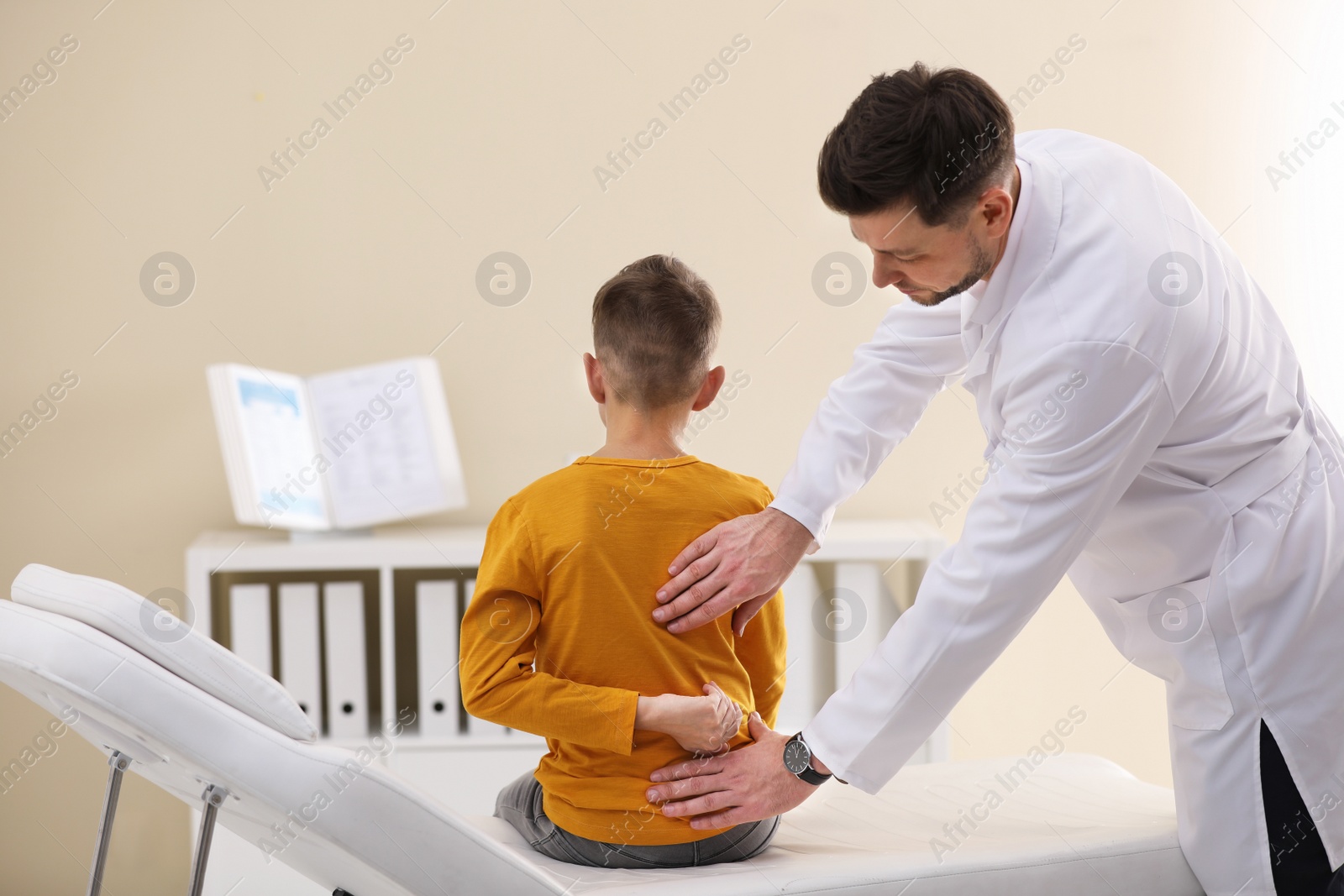 Photo of Chiropractor examining child with back pain in clinic