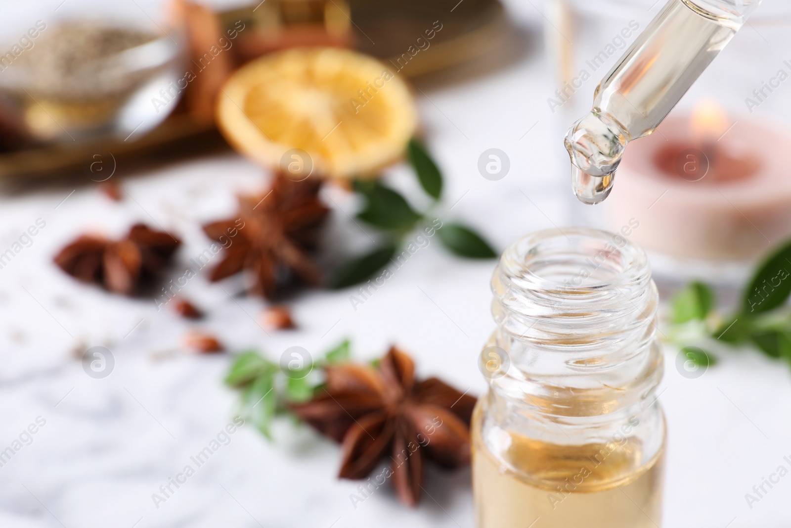 Photo of Dropping anise essential oil from pipette into bottle on table, closeup. Space for text