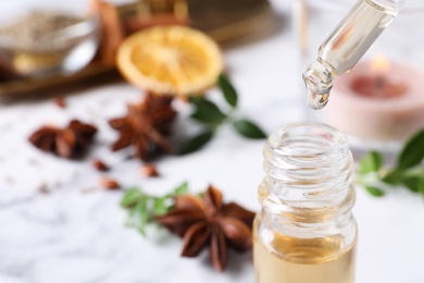 Photo of Dropping anise essential oil from pipette into bottle on table, closeup. Space for text