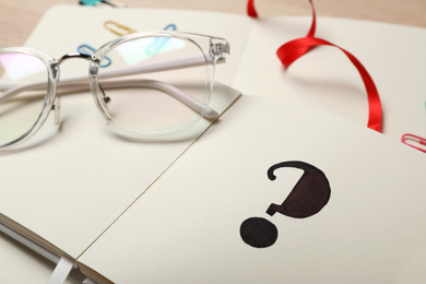 Photo of Question mark written in notebook and eyeglasses, closeup