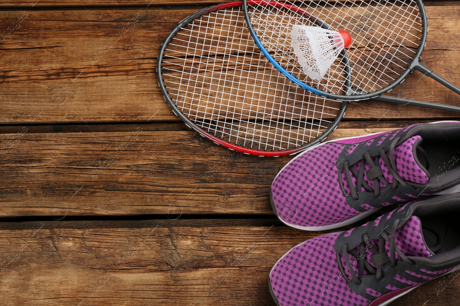 Photo of Rackets, shuttlecock and shoes on wooden table, flat lay with space for text. Playing badminton