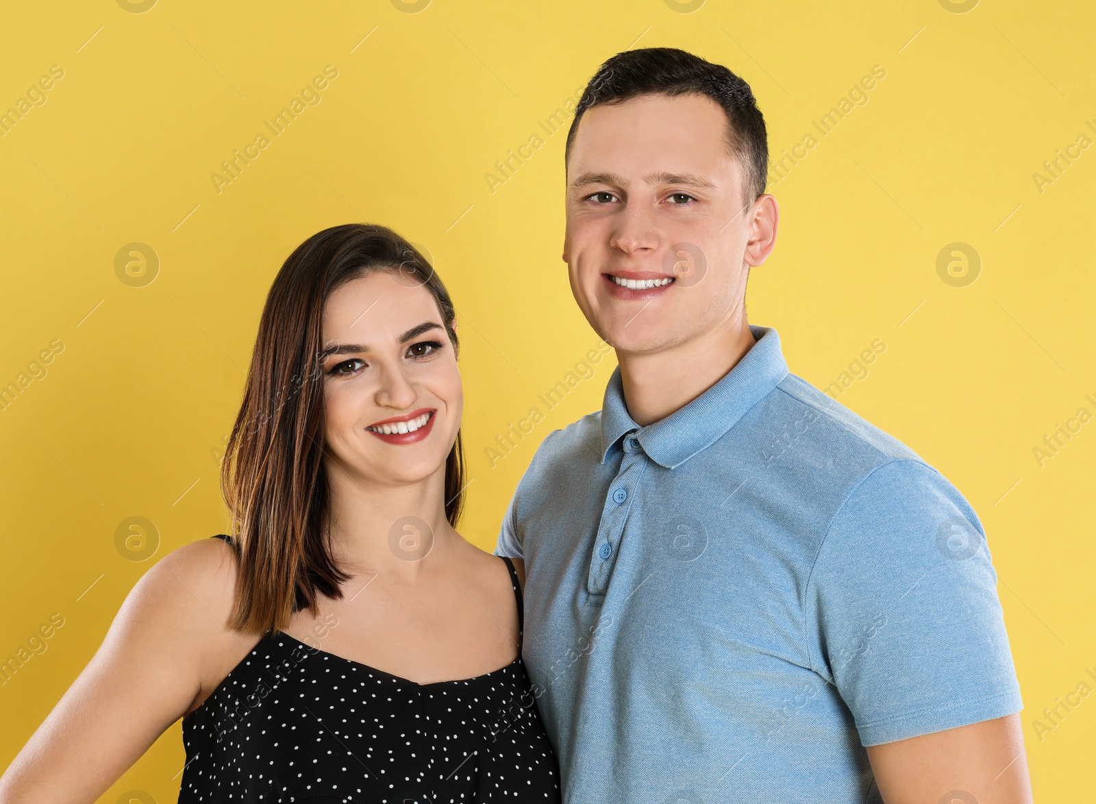 Photo of Happy young couple posing on yellow background