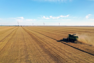 Photo of Modern combine harvester working in field on sunny day. Agriculture industry