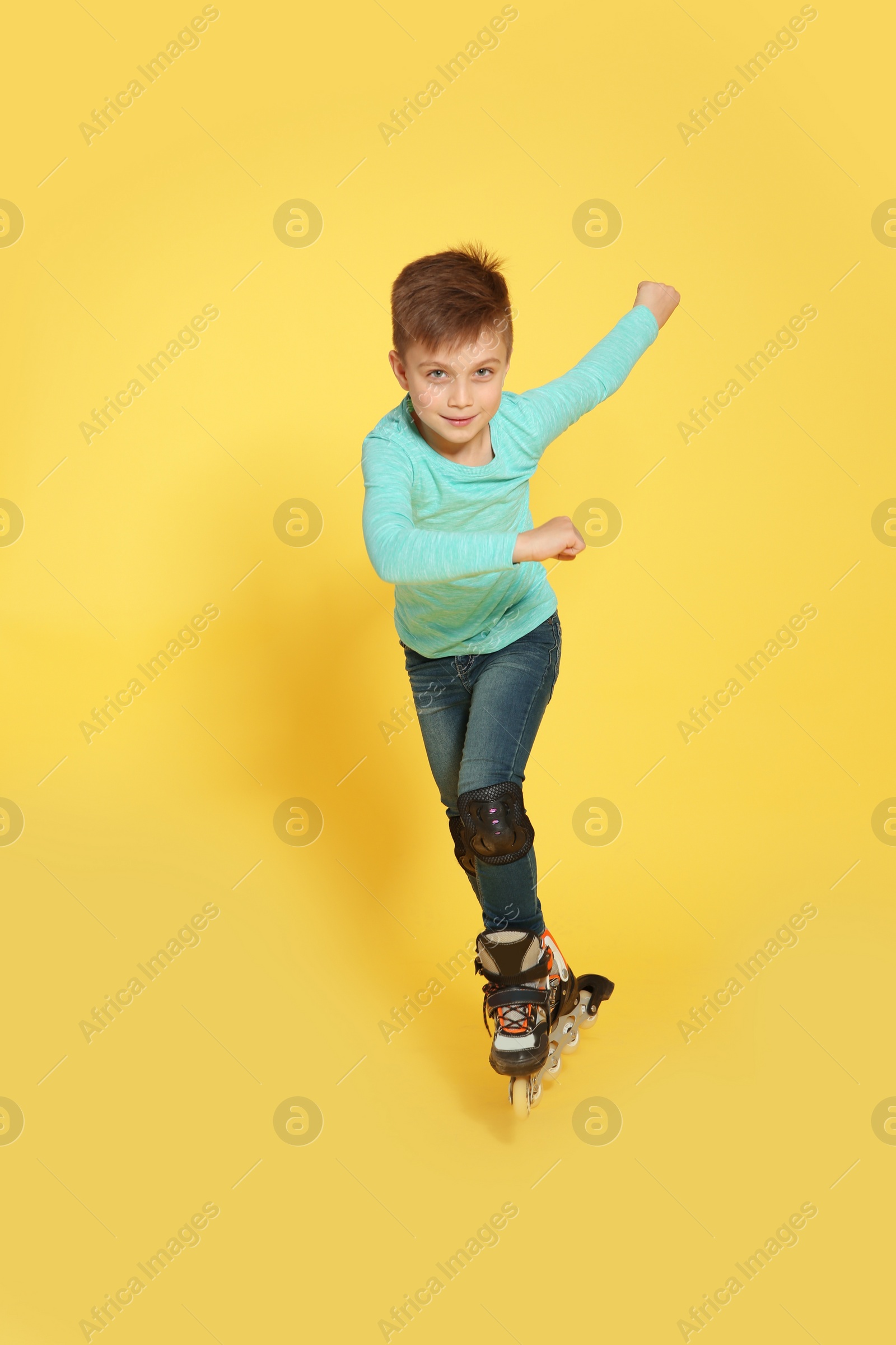 Photo of Little boy with inline roller skates on color background