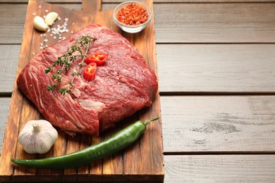 Photo of Fresh raw beef cut with spices on wooden table. Space for text