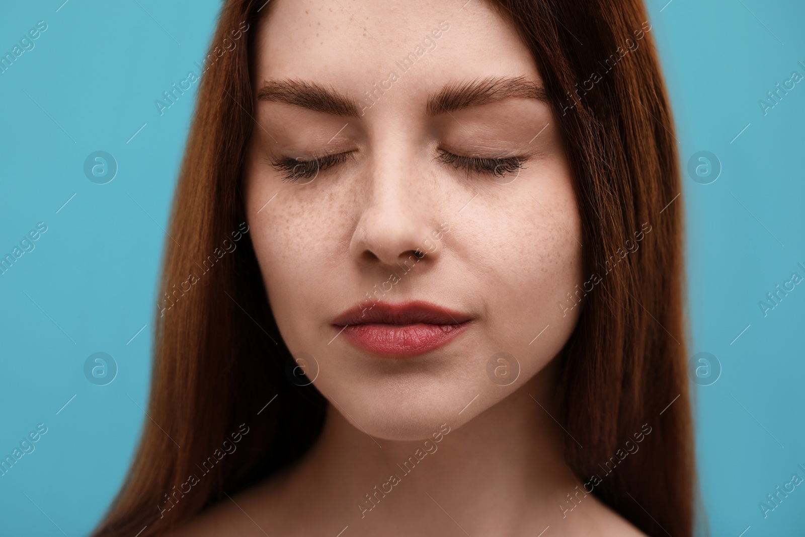 Photo of Portrait of beautiful woman with freckles on light blue background, closeup