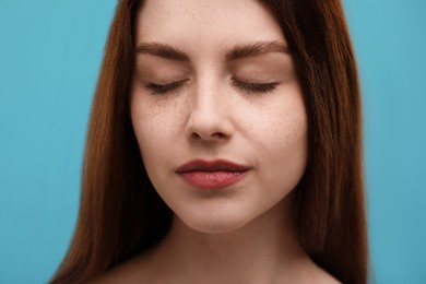 Photo of Portrait of beautiful woman with freckles on light blue background, closeup