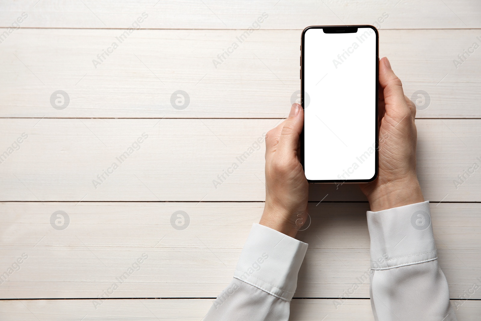 Photo of Woman with smartphone at white wooden table, top view. Space for text