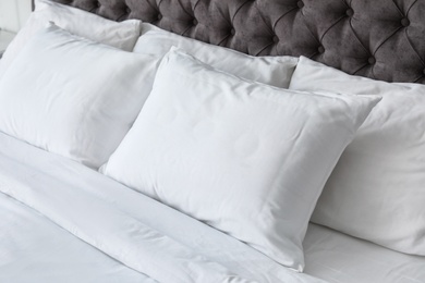 Photo of Soft white pillows on comfortable bed, closeup