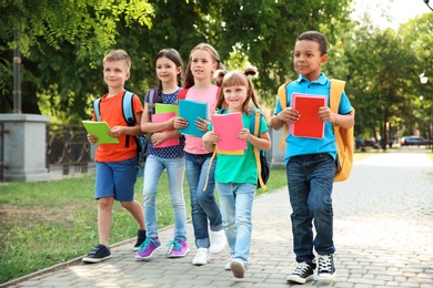 Photo of Cute little children with backpacks going to school