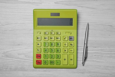 Calculator and pen on white wooden table, top view