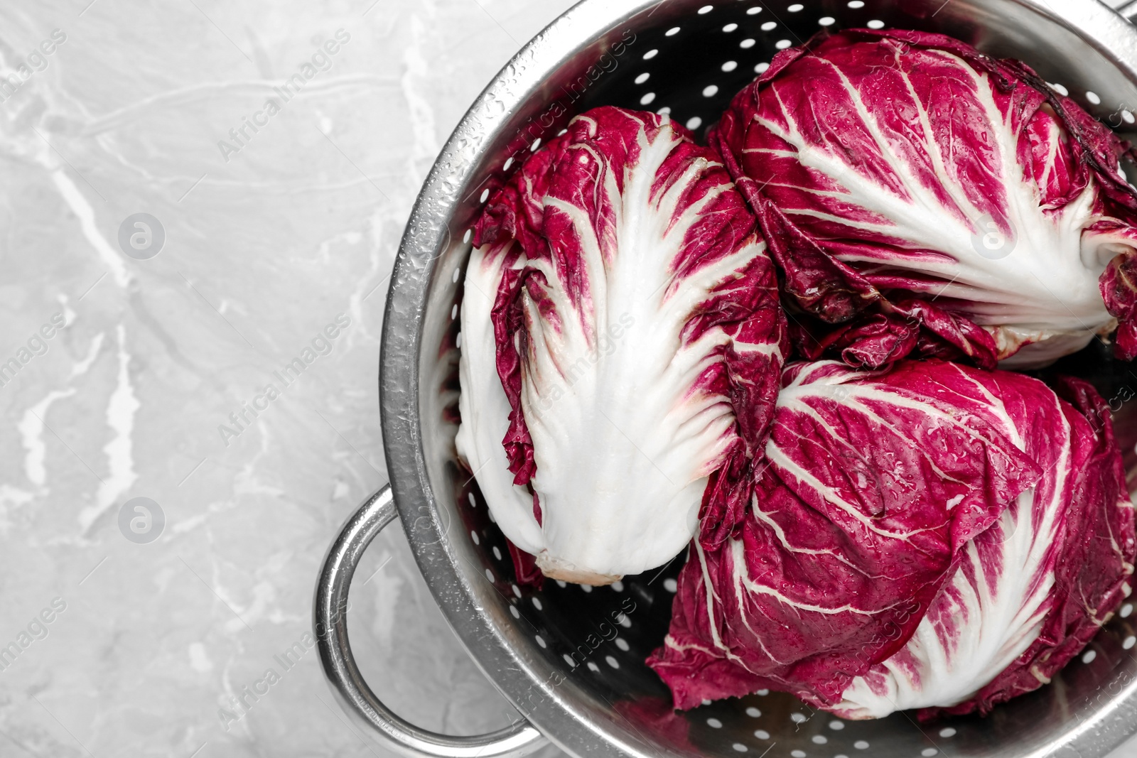 Photo of Fresh ripe radicchios in colander on light grey table, top view. Space for text