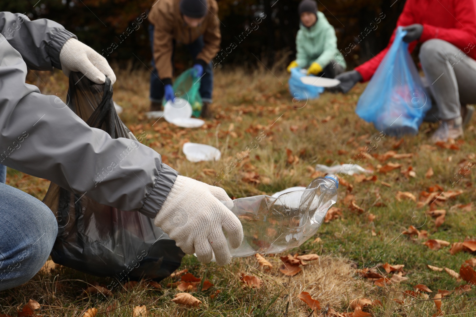 Photo of People with trash bags collecting garbage in nature, closeup