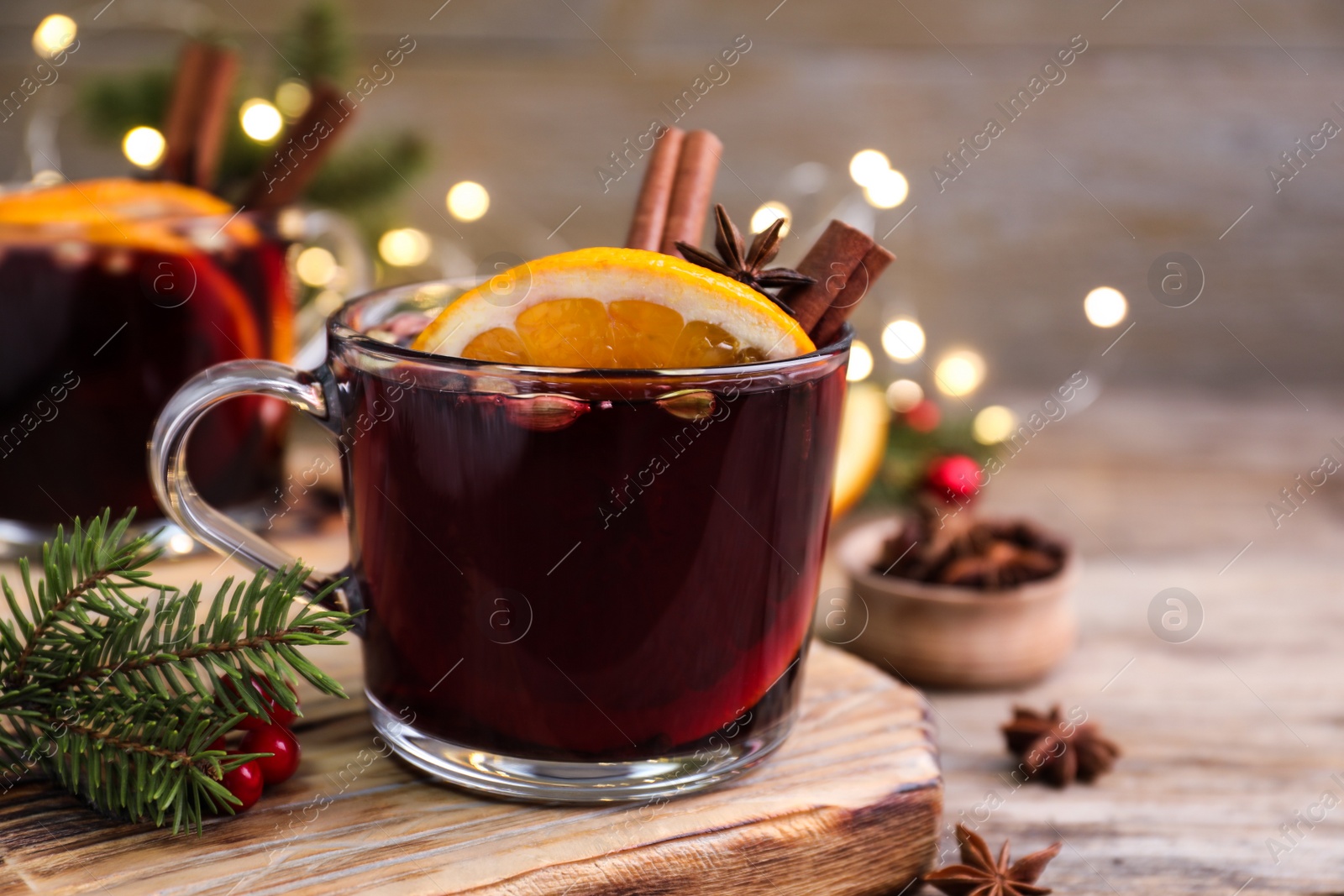 Photo of Aromatic mulled wine on wooden board, closeup