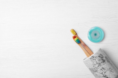 Flat lay composition with bamboo toothbrushes and space for text on white wooden background