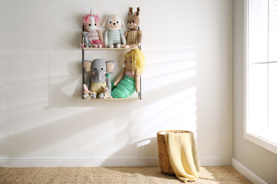 Photo of Shelf with cute toys on light wall indoors. Baby room interior element