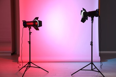 Photo of Photo background in neon lights and professional equipment inside modern studio