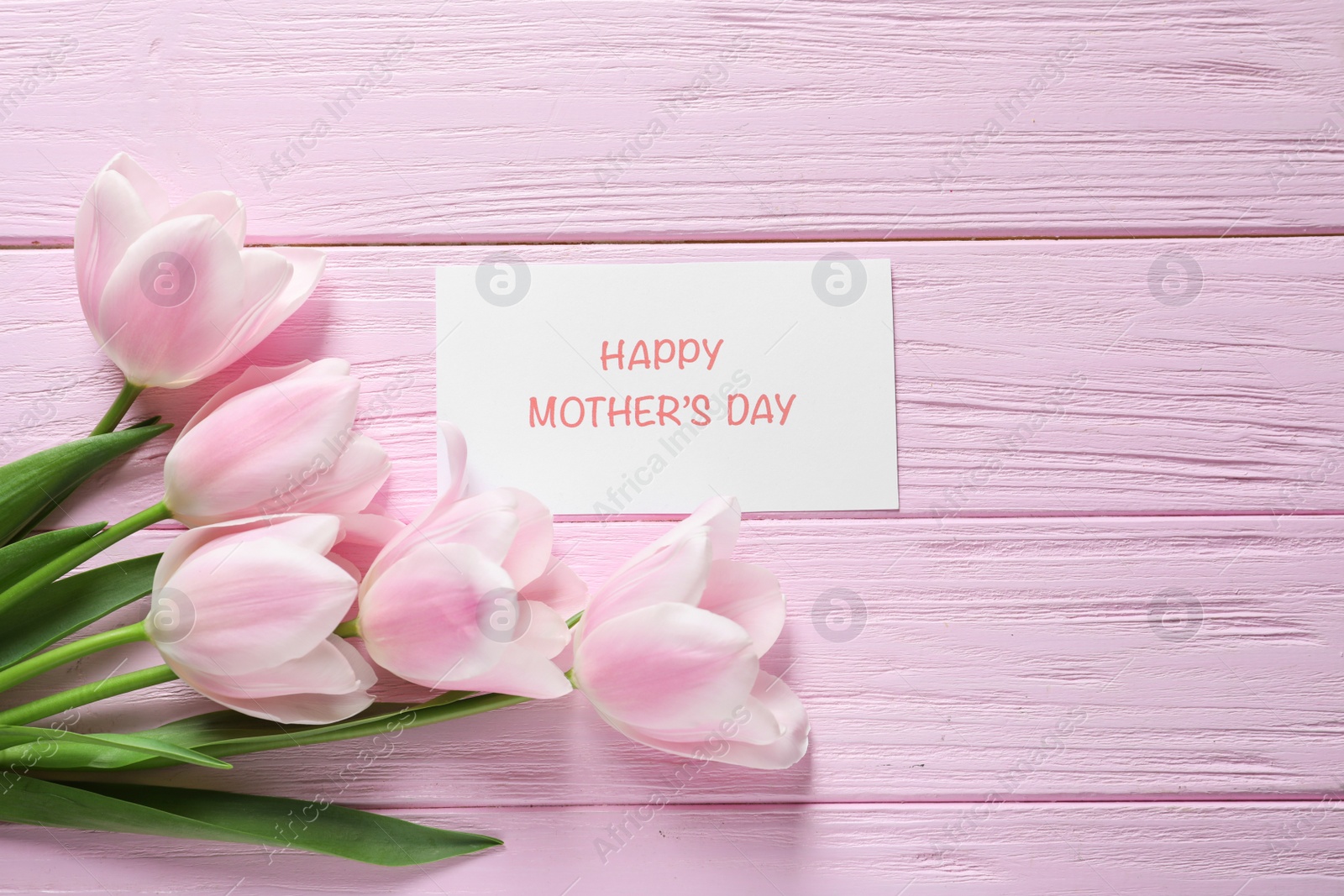 Photo of Tulips and greeting card with phrase "Happy Mother's Day" on wooden background