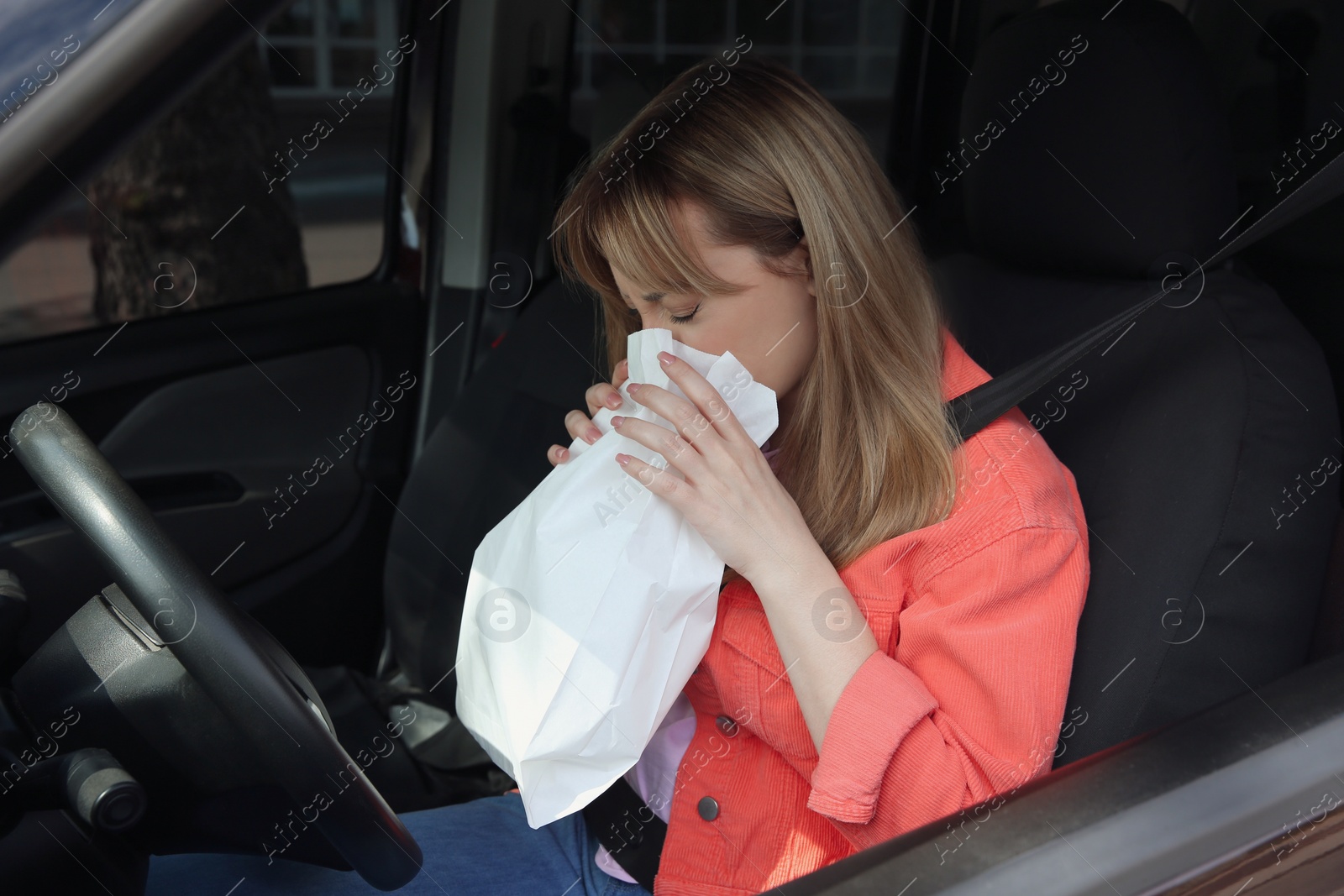 Photo of Woman with paper bag suffering from nausea in car