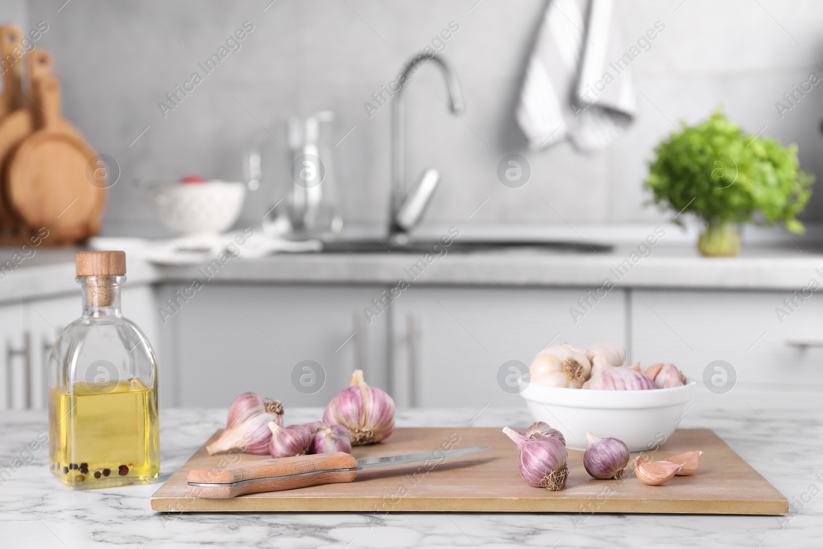 Photo of Fresh raw garlic, knife and oil on white marble table