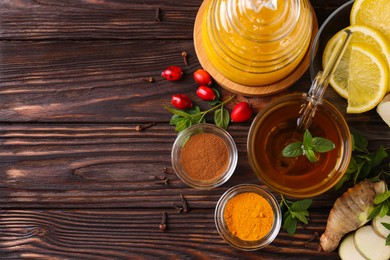 Photo of Flat lay composition of tea with honey and ingredients on wooden table. Space for text