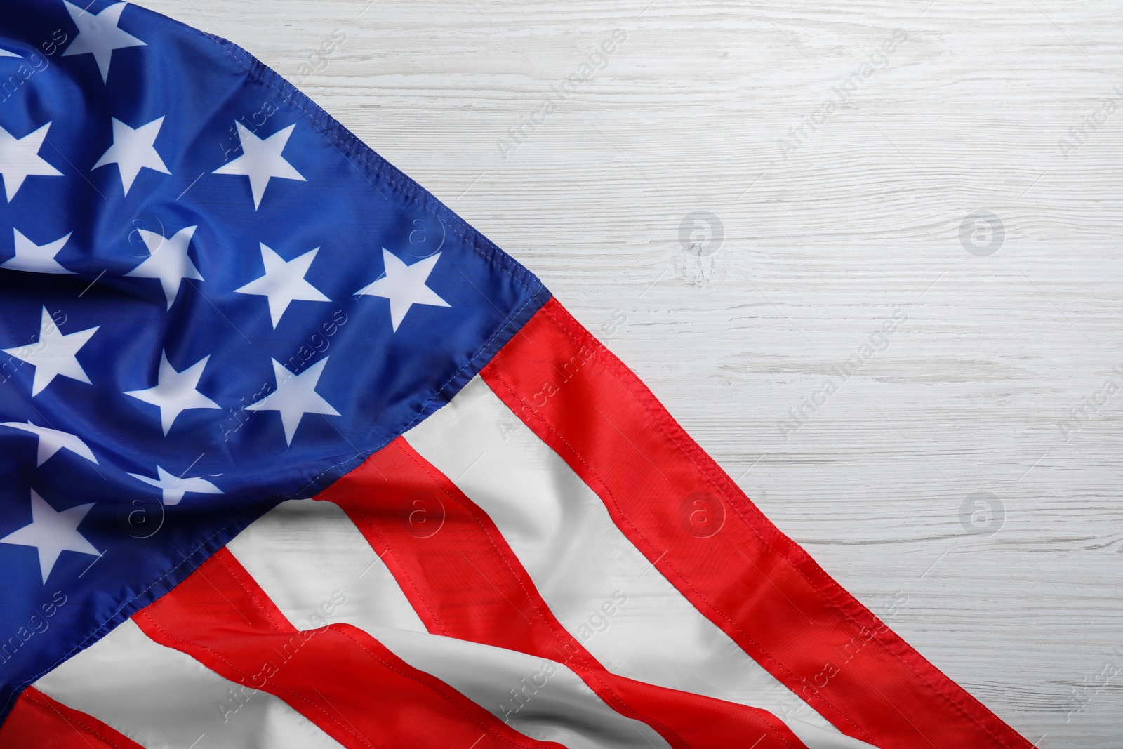 Photo of American flag on white wooden background, top view. Space for text