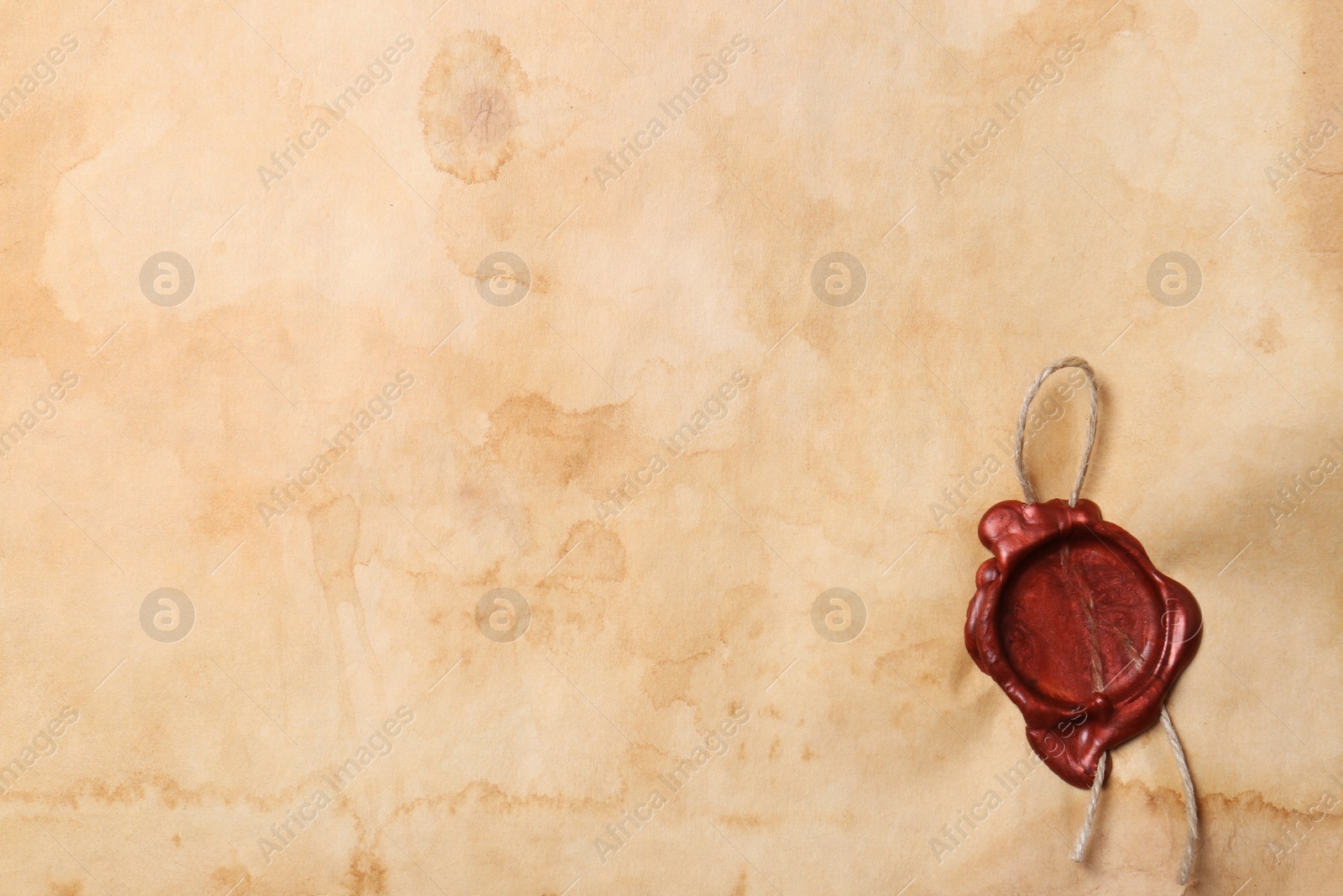 Photo of Sheet of old parchment paper with wax stamp as background, top view. Space for text