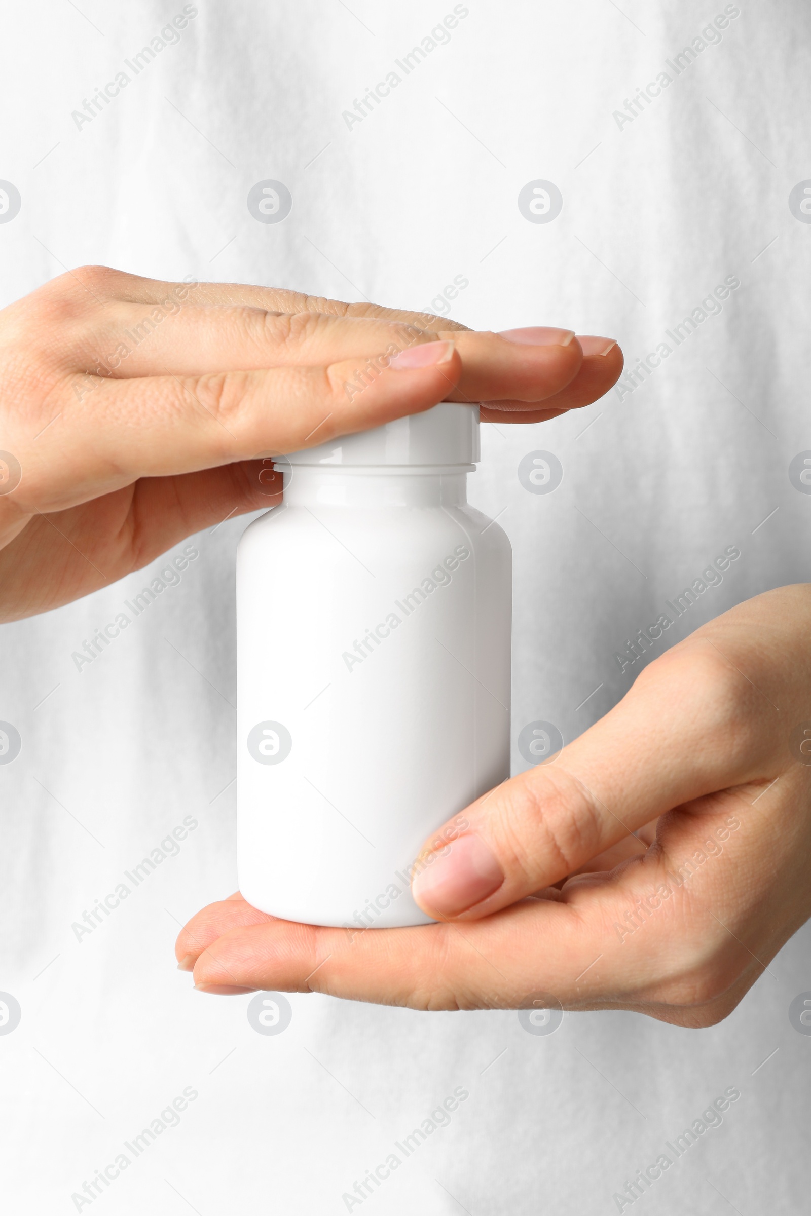 Photo of Woman holding one white pill bottle, closeup