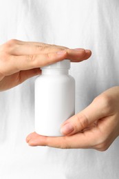 Photo of Woman holding one white pill bottle, closeup