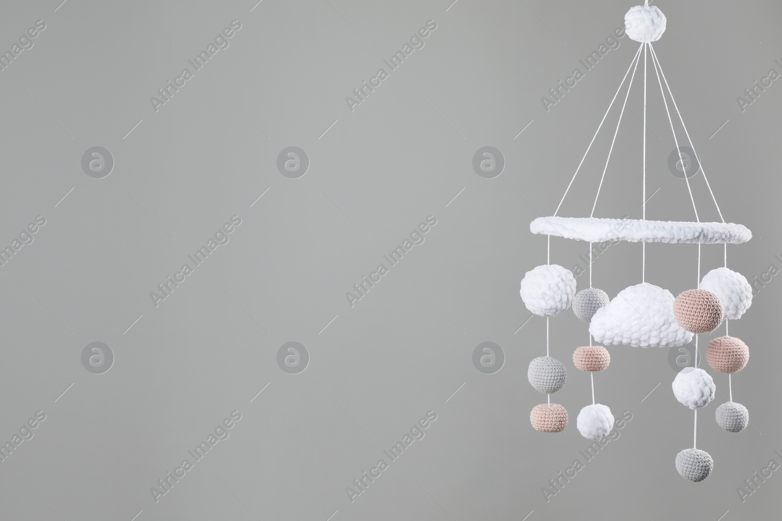 Photo of Cute baby crib mobile on grey background. Space for text