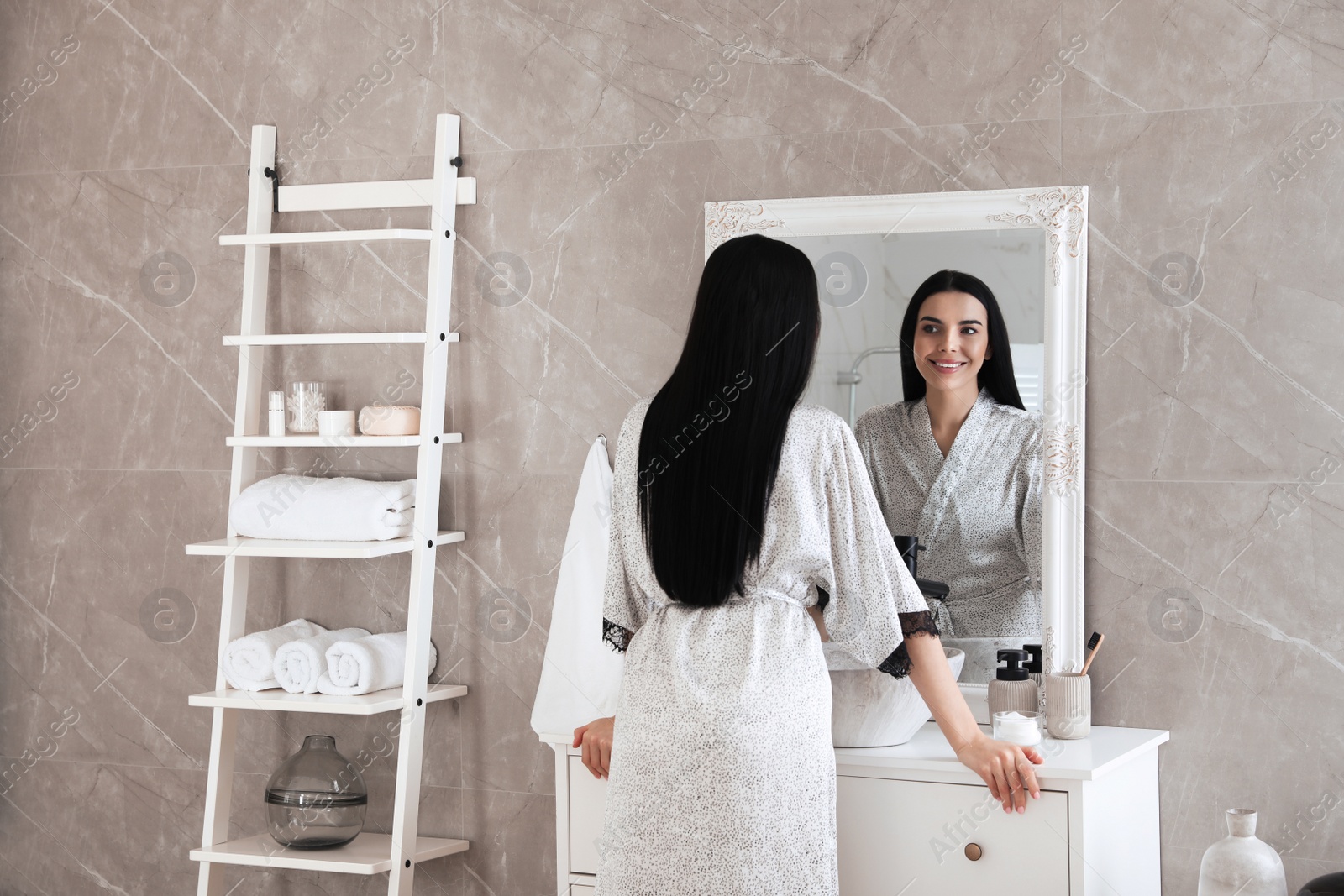 Photo of Beautiful young woman looking at herself in bathroom mirror