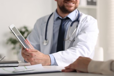 Professional doctor working with patient at white table in hospital, closeup