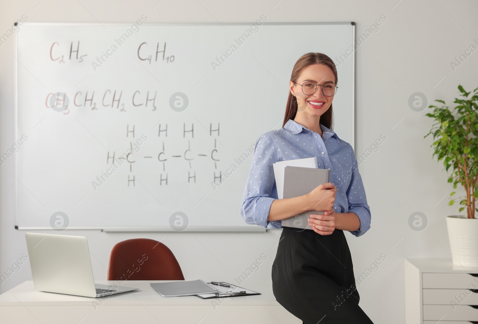 Photo of Portrait of young chemistry teacher near whiteboard in classroom. Space for text