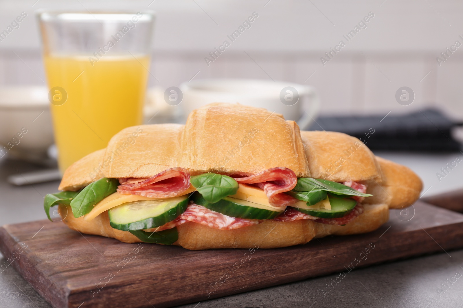 Photo of Wooden board with tasty croissant sandwich on table