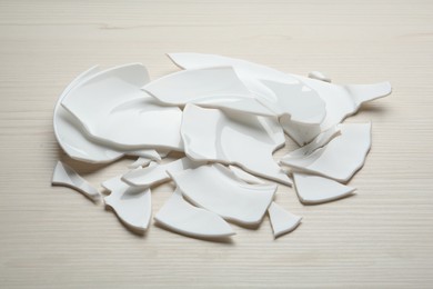 Pieces of broken ceramic plates on white wooden table