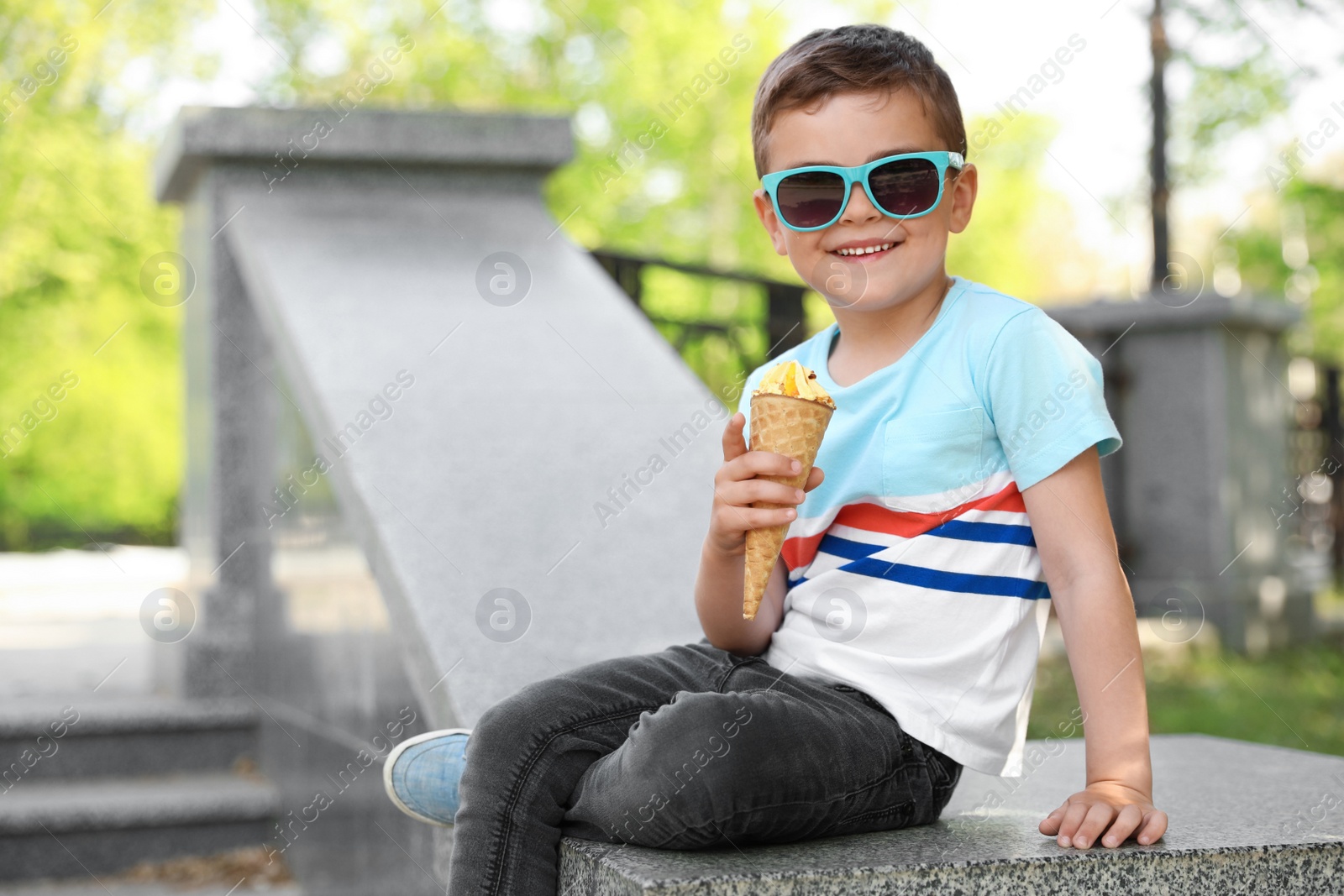 Photo of Cute little boy with delicious ice cream outdoors, space for text