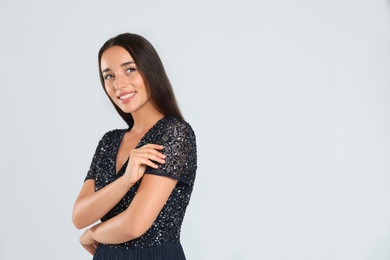 Young woman wearing stylish dress on light grey background. Space for text