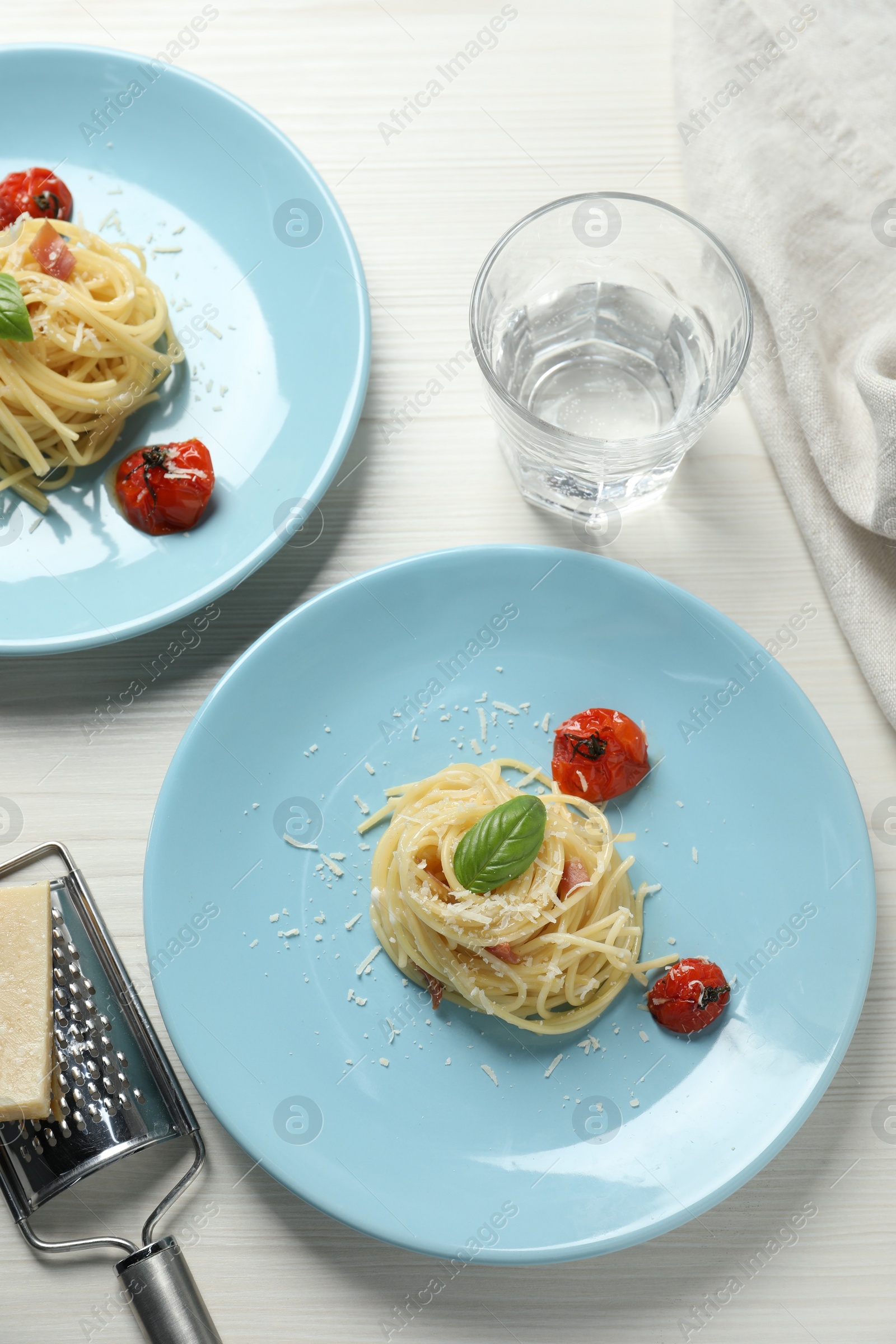 Photo of Tasty spaghetti with tomatoes and parmesan cheese served on white wooden table, flat lay. Exquisite presentation of pasta dish