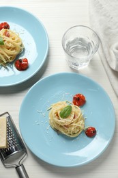 Tasty spaghetti with tomatoes and parmesan cheese served on white wooden table, flat lay. Exquisite presentation of pasta dish