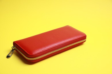 Stylish red leather purse on yellow background