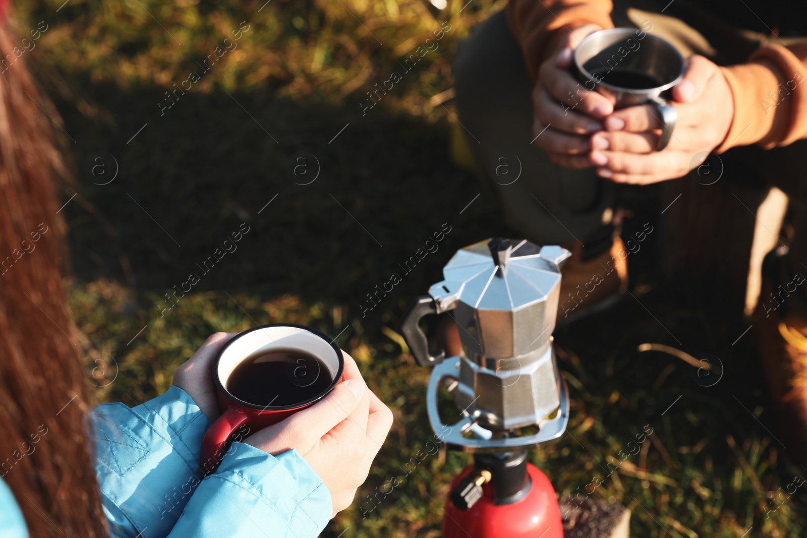 Photo of Young couple drinking coffee near camping tents outdoors, closeup