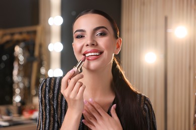 Photo of Bright makeup. Beautiful woman applying lipstick in dressing room
