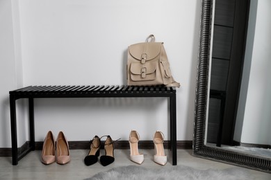 Stylish shoes near bench with backpack in hallway. Interior design