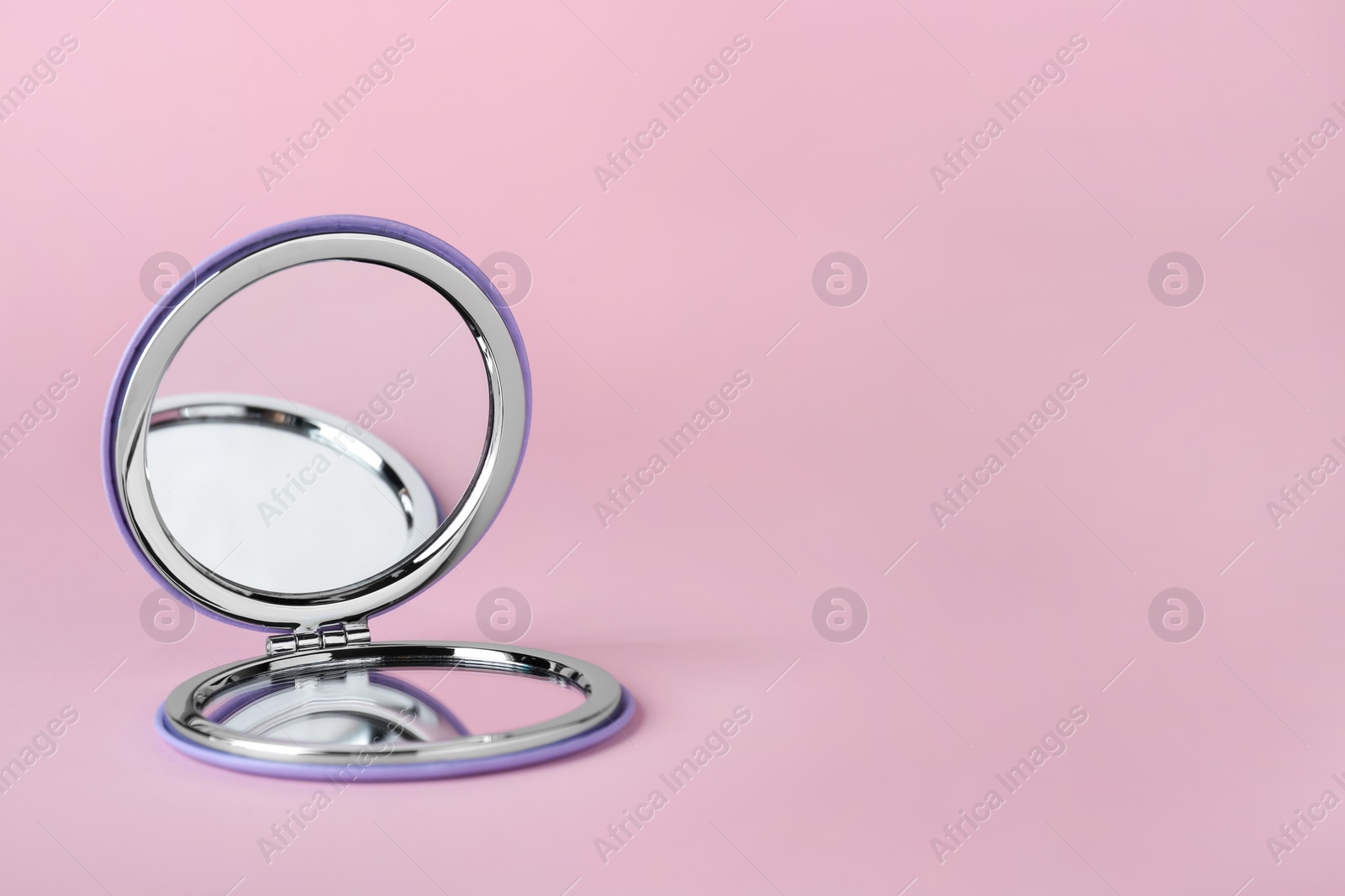 Photo of Stylish cosmetic pocket mirror on pink background. Space for text