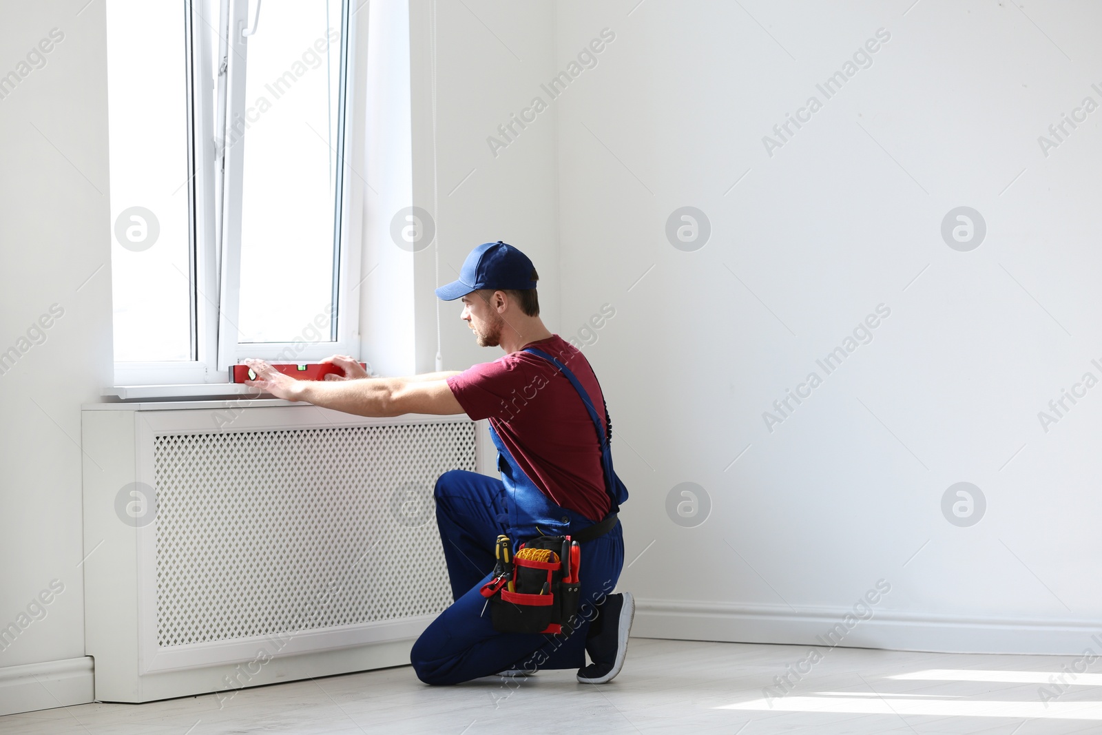 Photo of Handyman in uniform working with building level indoors. Professional construction tools