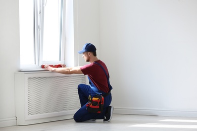 Photo of Handyman in uniform working with building level indoors. Professional construction tools