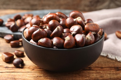 Photo of Fresh sweet edible chestnuts on wooden table, closeup