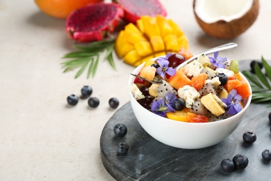 Photo of Delicious exotic fruit salad in bowl on light grey table