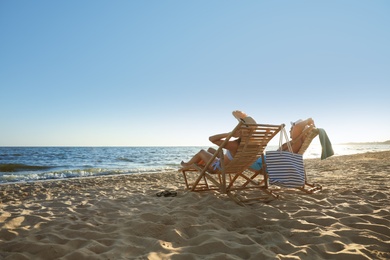 Photo of Young couple relaxing in deck chairs on beach near sea