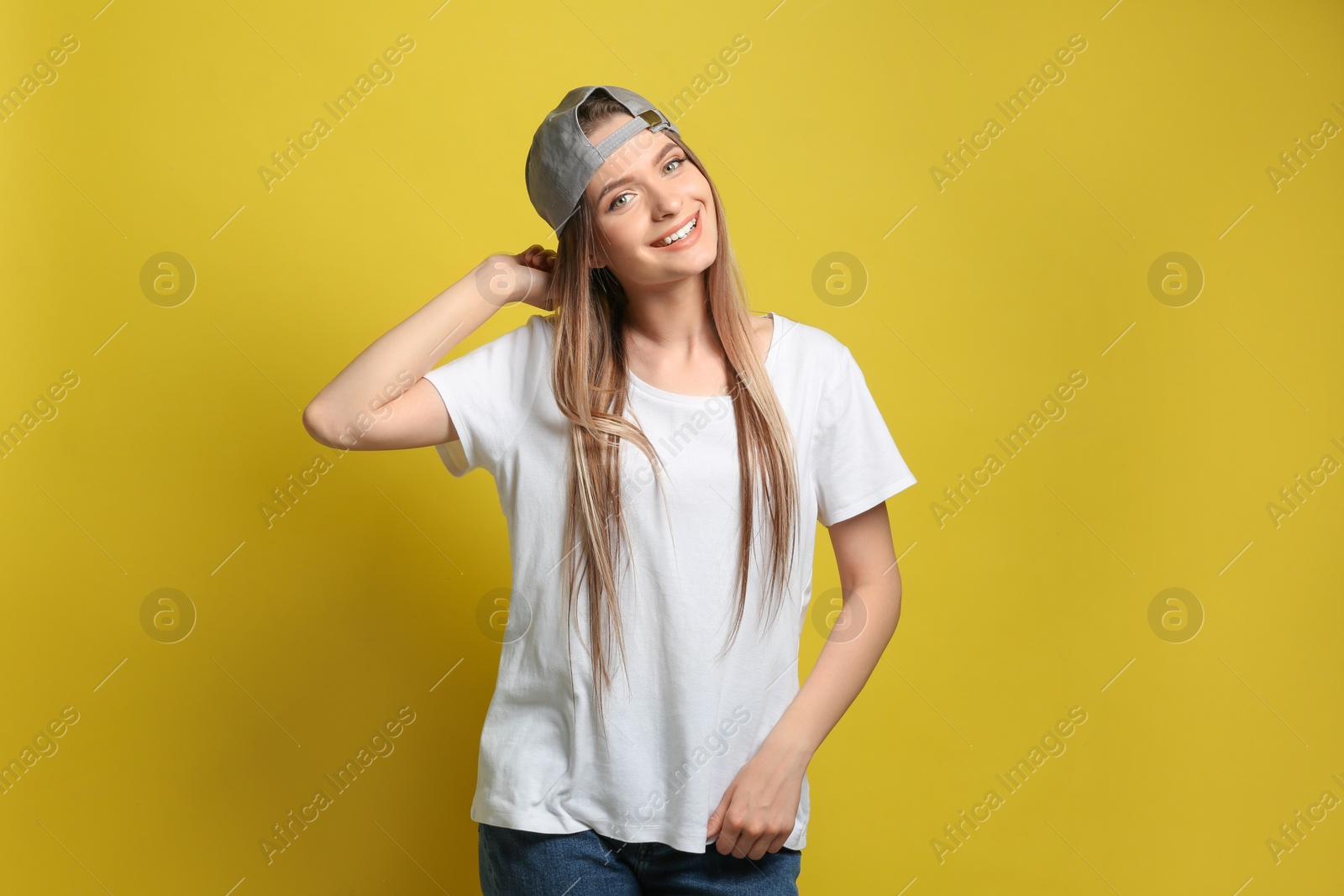 Photo of Young woman wearing blank t-shirt on yellow background. Mockup for design